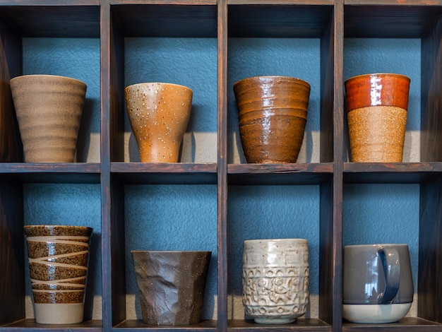 Diverses tasses en céramique sur une étagère en bois