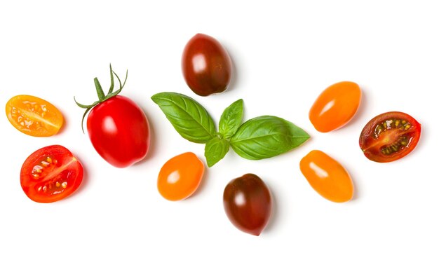 Diverses tomates colorées et feuilles de basilic isolées sur fond blanc Vue de dessus mise à plat Mise en page créative