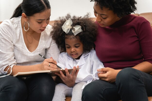 Diversité LGBT Moments de couple lesbien Bonheur avec sa fille africaine riant et dessinant une photo, mode de vie LGBT.