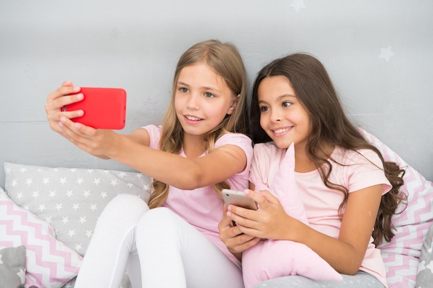 Divertissement en ligne. Explorez le réseau social. Smartphone pour le divertissement. Enfants prenant selfie. Concept d'application pour smartphone. Soirée pyjama de loisirs pour filles. Filles smartphone petits blogueurs.