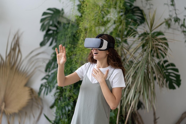 Divertissement virtuel au jardin de la maison femme ravie dans un casque vr jouant à un jeu vidéo interactif