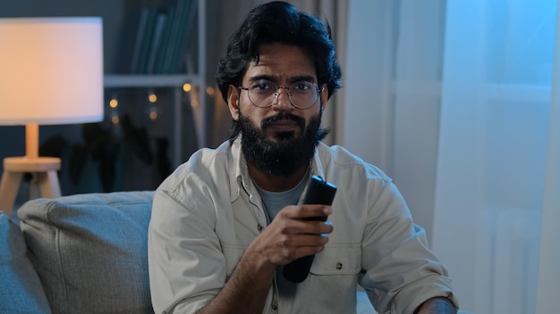 Divertissements en soirée homme indien arabe homme barbu dans des verres dans l'obscurité vivant à la maison guy est assis