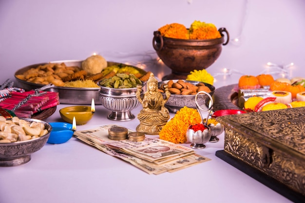 Diwali et préparation pour Laxmi ou Lakshmi Pooja avec des éléments tels que diya, billets de banque, bonbons, fleurs, collations, haldi et kumkum