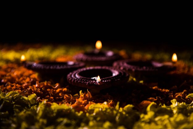 Diya ou lampe à huile traditionnelle allumée sur rangoli coloré composé de pétales de fleurs, sur le festival des lumières appelé diwali ou deepawali, mise au point sélective