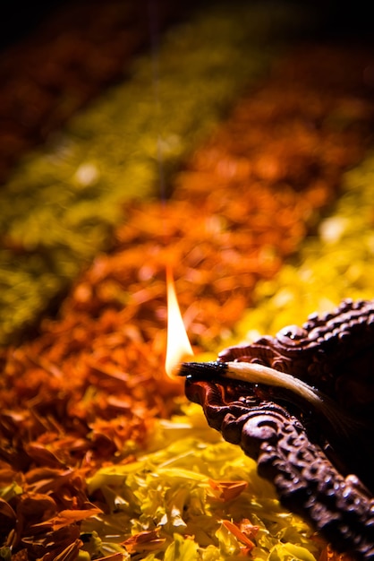 Diya ou lampe à huile traditionnelle allumée sur rangoli coloré composé de pétales de fleurs, sur le festival des lumières appelé diwali ou deepawali, mise au point sélective