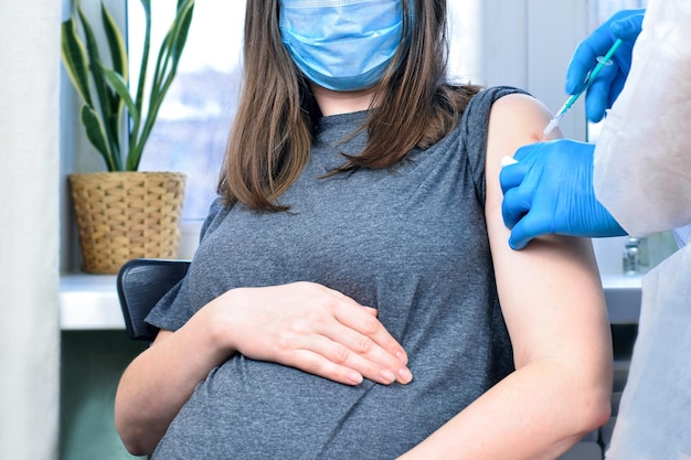 Photo docteur administrant une injection de vaccin contre le covid-19 à une femme enceinte