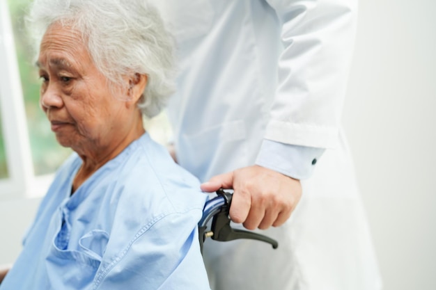 Docteur aide une femme âgée asiatique handicapée assise sur un fauteuil roulant dans un concept médical d'hôpital