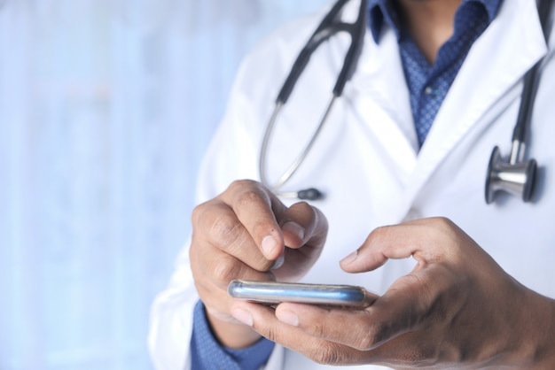 Docteur en blouse blanche à l'aide d'un smartphone.