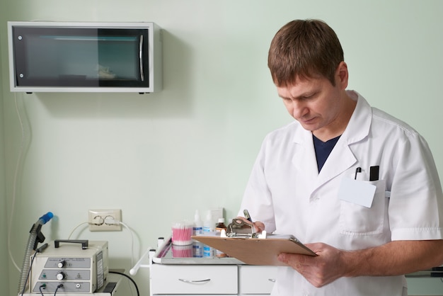 Docteur, blouse blanche, debout, tenue, presse-papiers, écriture, diagnostic