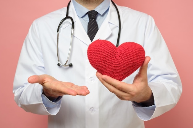 Docteur en blouse blanche tenant un gros coeur rouge dans les mains