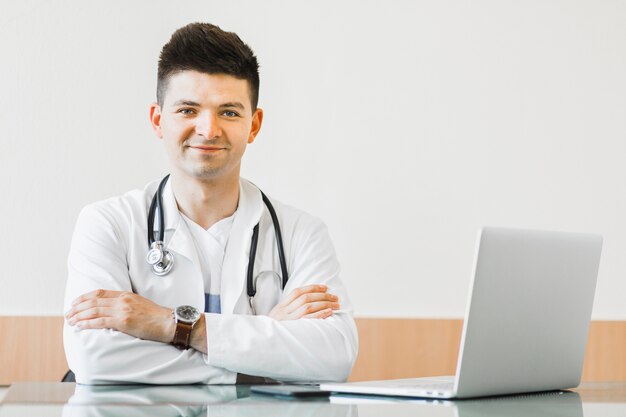 Photo docteur avec les bras croisés au bureau