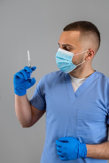 Docteur caucasien professionnel tenant une seringue avec un vaccin isolé sur le gris