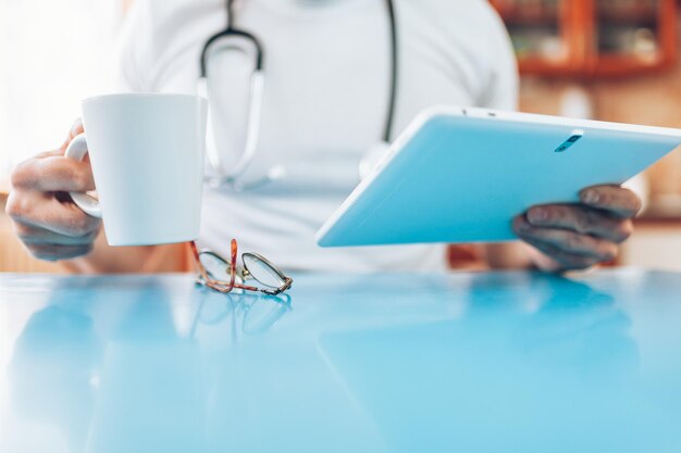 Docteur dans sa pratique avec une tablette numérique