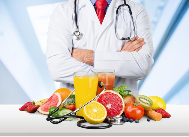 Docteur debout avec les bras croisés sur fond de fruits et légumes