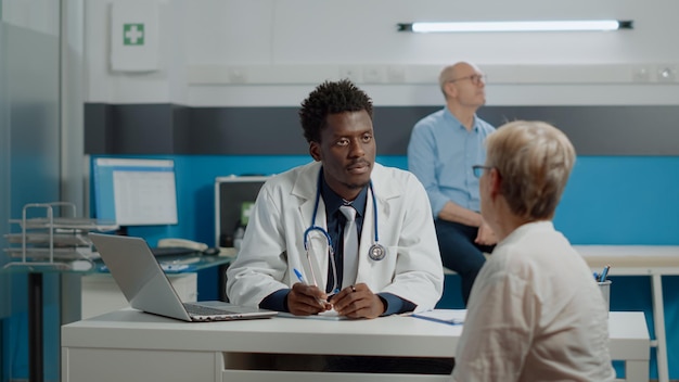 Docteur discutant avec un patient avec une femme en arrière-plan à l'hôpital