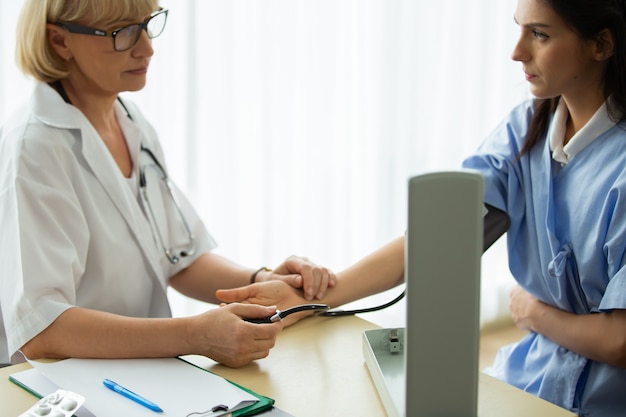 Docteur donnant des conseils et patient souriant discutant de quelque chose tout en étant assis à la table