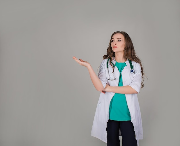 le docteur est une femme dans un manteau blanc et des gants sur un fond gris