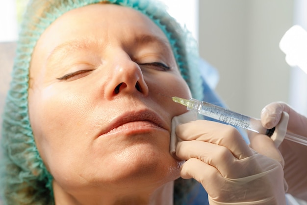 Docteur esthéticienne fait des injections dans le front pour la beauté du patient. Injections de beauté en cosmétologie. Le concept de beauté.