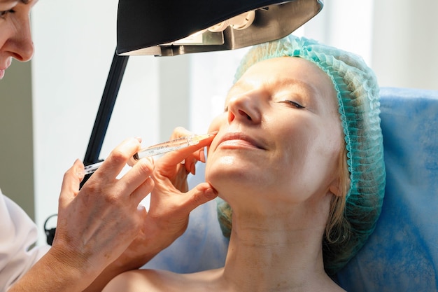 Docteur esthéticienne fait des injections dans le front pour la beauté du patient. Injections de beauté en cosmétologie. Le concept de beauté.