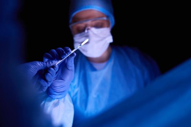 Docteur exécutant la chirurgie dans un fond foncé