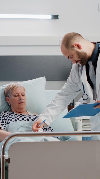 Docteur faisant la consultation avec le patient retraité pour les soins de santé dans la salle d'hôpital. Un médecin parle à une femme malade pendant qu'une infirmière apporte son soutien à l'examen médical et au rétablissement. Équipe médicale