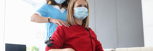 Le docteur fait le massage d'épaule à une femme dans un fauteuil roulant