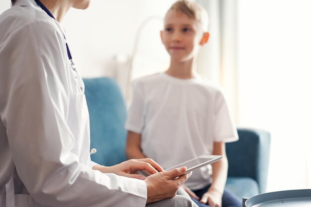 Docteur femme et enfant patient à la maison Le pédiatre utilisant une tablette tout en remplissant les dossiers médicaux de près les concepts de soins de santé de la médecine