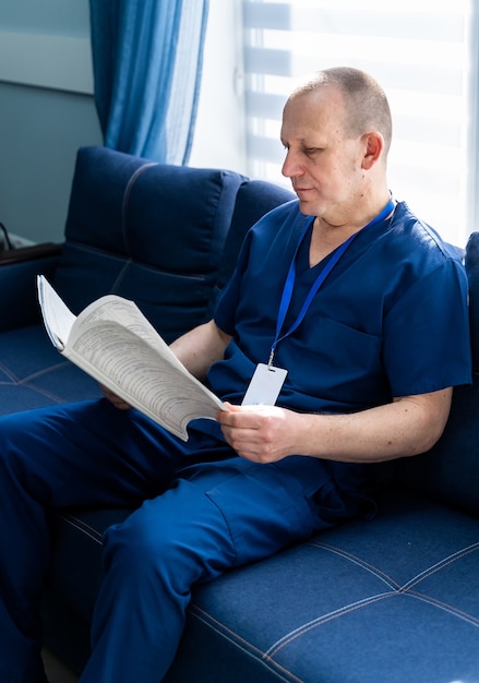 Docteur en gommages lisant des documents. Assis sur un canapé dans un cabinet médical.