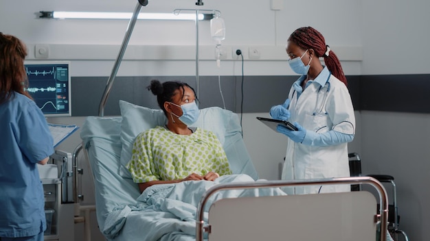 Docteur avec infirmière examinant un patient dans un service de l'hôpital