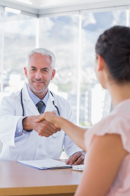 Docteur joyeux serrant la main au patient