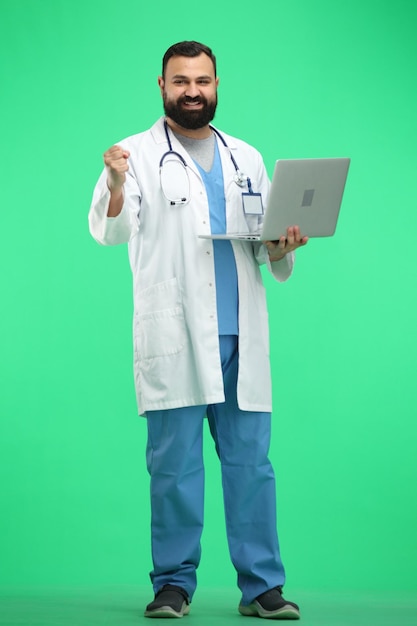 Docteur masculin en pleine longueur sur un fond vert avec un ordinateur portable