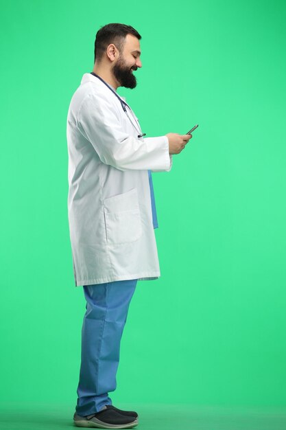 Docteur masculin en pleine longueur sur un fond vert avec un téléphone