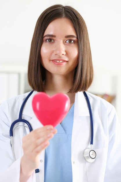 Docteur en médecine féminin tenir dans les mains coeur de jouet rouge