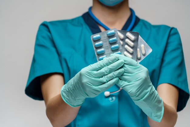 Docteur en médecine infirmière femme portant un masque de protection et des gants en caoutchouc ou en latex - tenant des ampoules de pilules