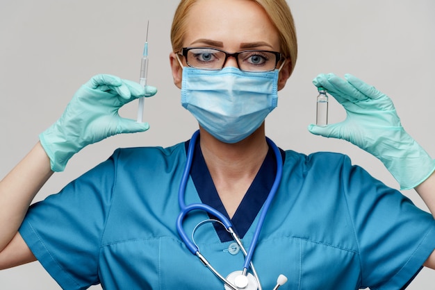 Docteur en médecine infirmière femme portant un masque de protection et des gants tenant une seringue