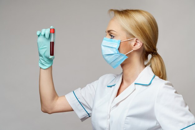 Docteur en médecine infirmière femme portant un masque de protection et des gants - tenant un test sanguin de virus