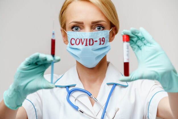 Docteur en médecine infirmière femme portant un masque de protection et des gants tenant un tube à essai sanguin et une seringue