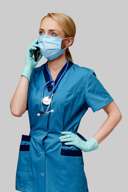 Docteur en médecine infirmière femme avec stéthoscope portant un masque de protection et des gants en caoutchouc ou en latex parler sur téléphone portable