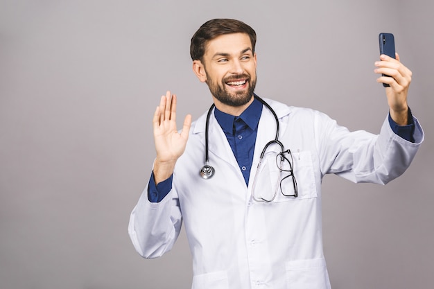 Docteur en médecine prenant un selfie avec caméra frontale et souriant à son lieu de travail