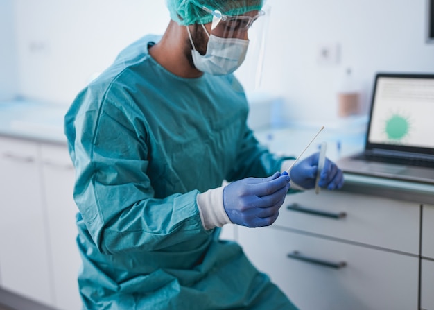 Docteur en médecine tenant un test de coton-tige à l'intérieur de l'hôpital - Procédure d'identification du code qr du laissez-passer vert