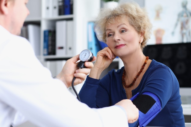 Le docteur mesure la tension artérielle d'une femme âgée