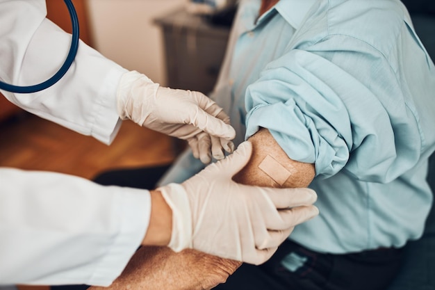 Docteur mettant un plâtre à la place de l'injection de vaccin à un patient âgé