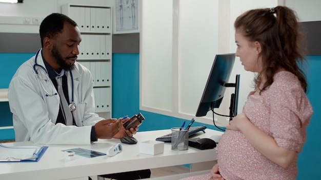 Docteur montrant des médicaments à une femme enceinte à la clinique