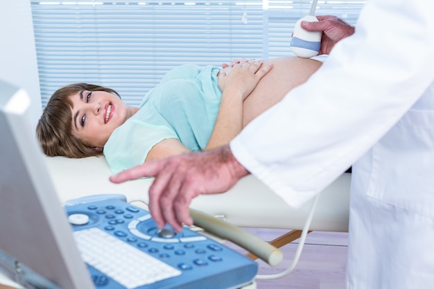 Docteur montrant le moniteur échographique à la femme enceinte heureuse