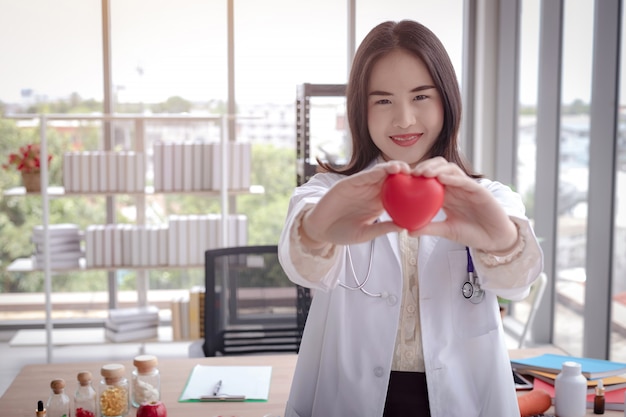 Photo le docteur montre un coeur rouge au bureau