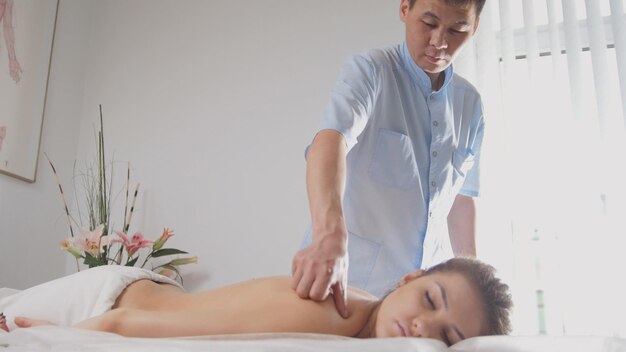 Docteur osteopat et patient - jeune femme allongée sur une table de massage - traitement médical, gros plan