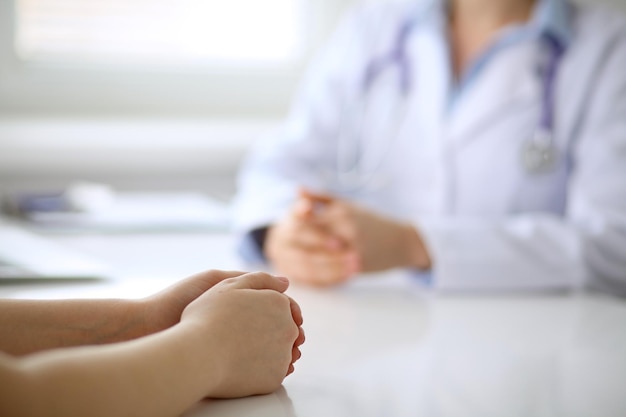 Le docteur et le patient discutent quelque chose, juste des mains à la table.