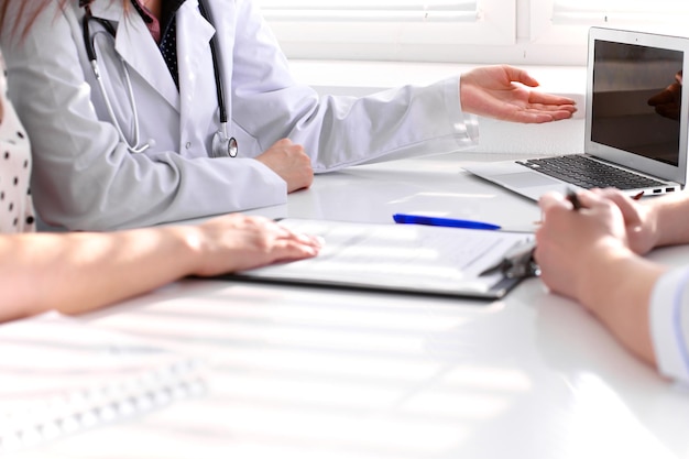 Le docteur et le patient discutent quelque chose, juste des mains à la table.