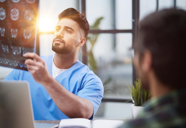 Le docteur et le patient à la réception discutent des rayons X des sinus.