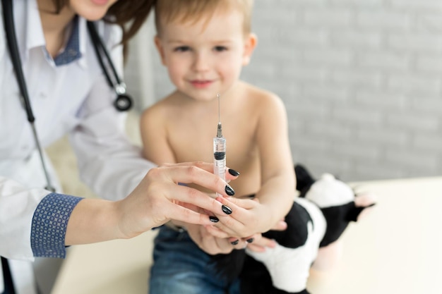 Docteur pédiatre joue avant l'injection avec le garçon.